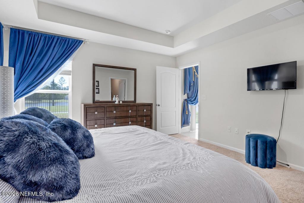 86178 Mainline Road Yulee, FL 32097 - Photo 27 of 61 a spacious bedroom with a bed and a flat screen tv