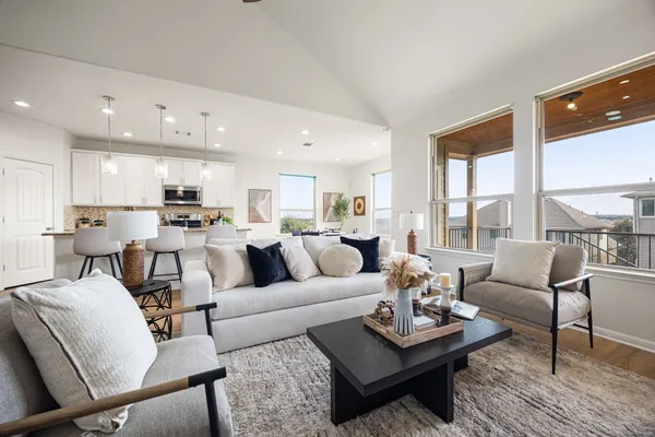a living room with furniture kitchen view and large windows