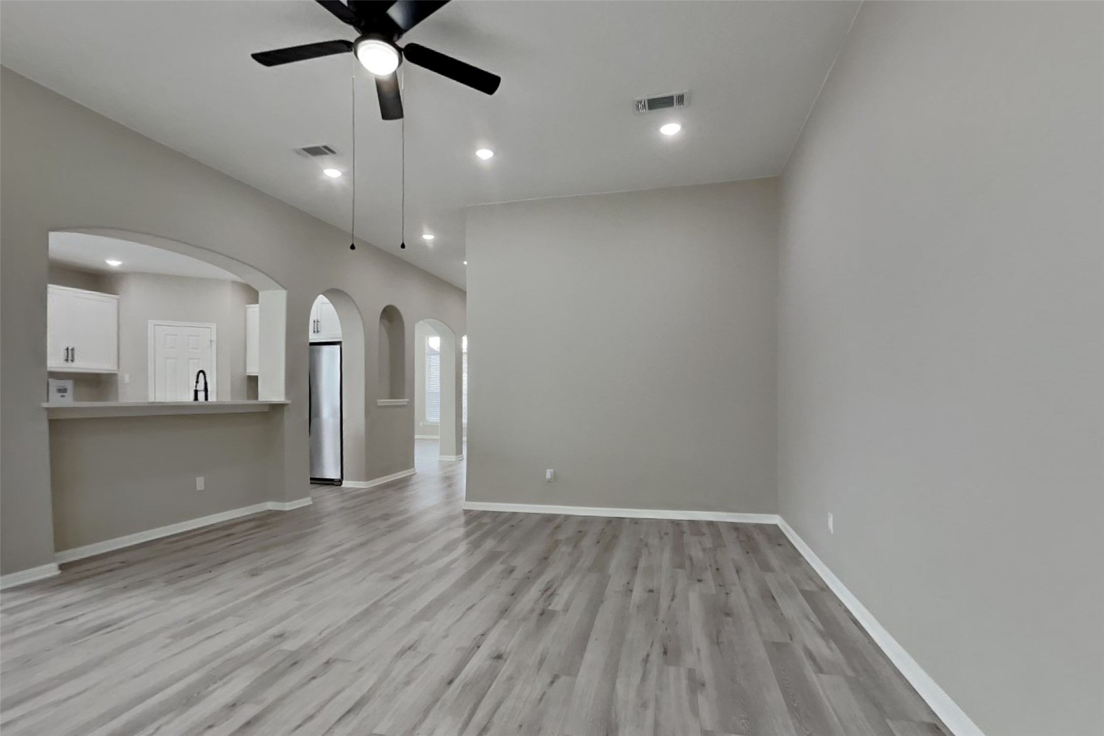 2014 Ridgeway Park Drive Houston, TX 77339 - Photo 4 of 19 an empty room with wooden floor a ceiling fan and kitchen view