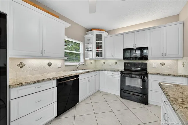 a kitchen with granite countertop white cabinets and stainless steel appliances
