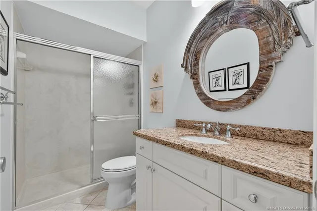 a bathroom with a granite countertop toilet a sink and a mirror