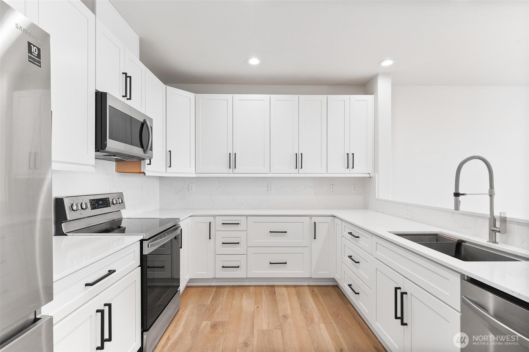 14915 38th Drive Southeast, Unit F3011 Bothell, WA 98012 - Photo 4 of 40 a kitchen with white cabinets a sink dishwasher and a stove with wooden floor