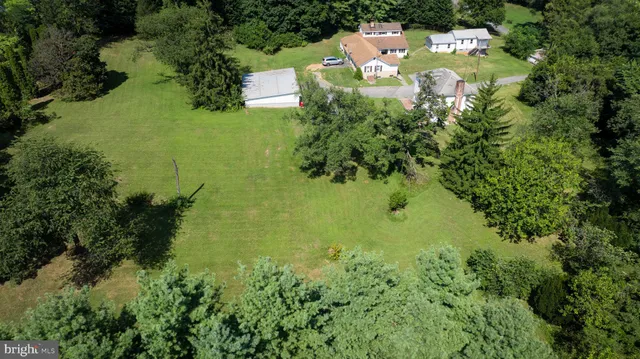 an aerial view of residential houses with outdoor space and trees all around