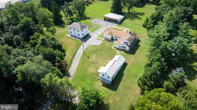 an aerial view of a house with outdoor space and trees all around