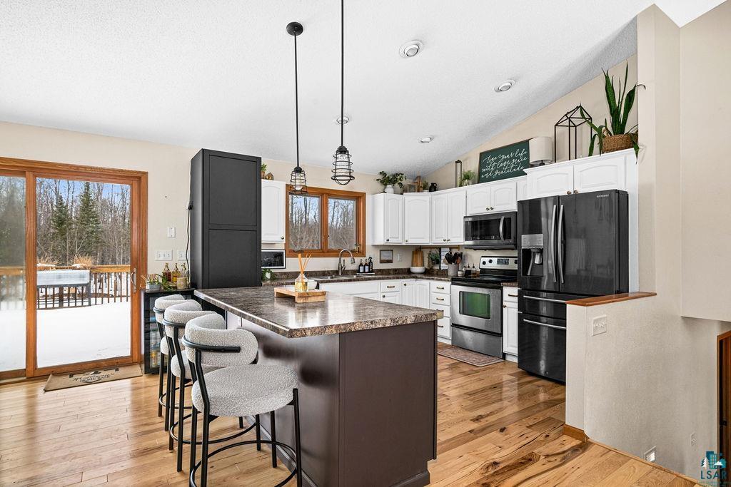 2783 Lauren Road Duluth, MN 55804 - Photo 2 of 47 Kitchen featuring stainless steel appliances, white cabinetry, a breakfast bar, a kitchen island, and dark countertops