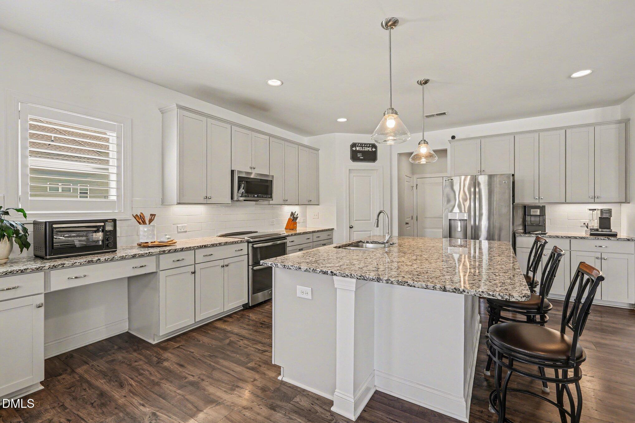 432 Seabring Lane Raleigh, NC 27603 - Photo 10 of 29 a kitchen with kitchen island granite countertop a sink stove and white cabinets