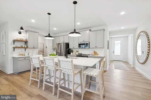 a kitchen with stainless steel appliances kitchen island granite countertop a dining table chairs and white cabinets