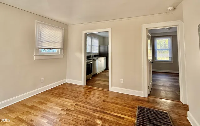 a view of an empty room with wooden floor and a window
