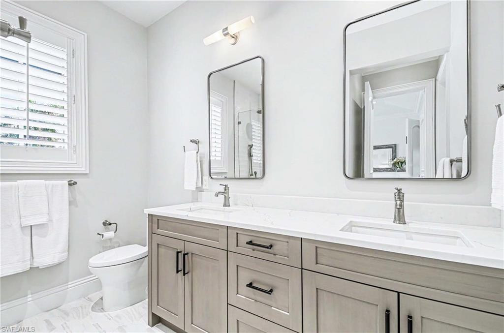 1888 6th Street South Naples, FL 34102 - Photo 30 of 37 a bathroom with a toilet a sink a vanity and mirror