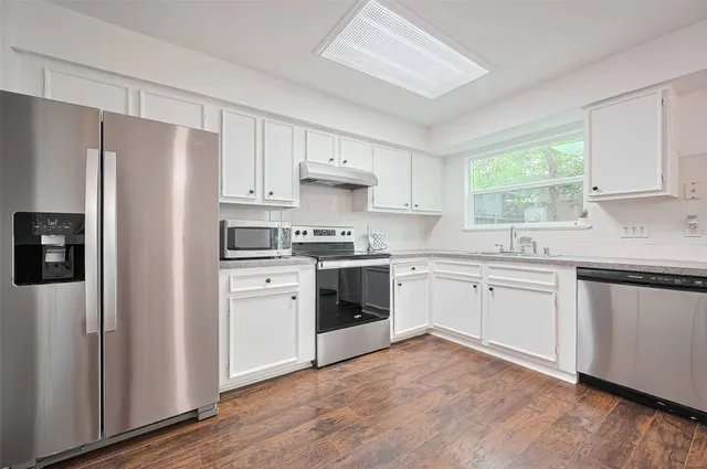 a kitchen with granite countertop white cabinets and white stainless steel appliances