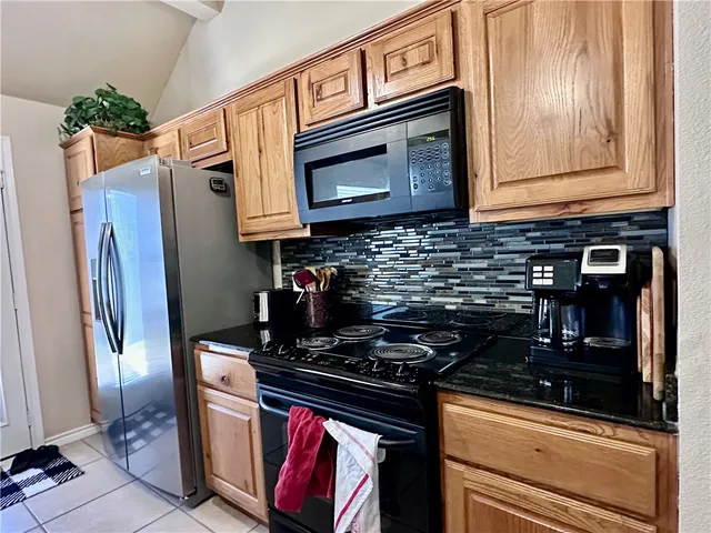 a kitchen with stainless steel appliances granite countertop a stove a refrigerator and a microwave
