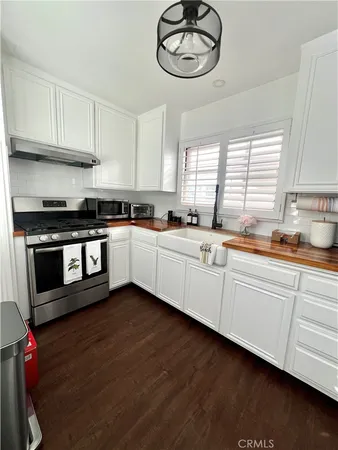 a kitchen with stainless steel appliances granite countertop a sink a stove cabinets and wooden floor