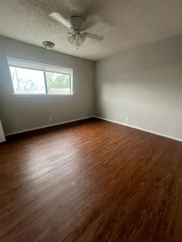 an empty room with wooden floor cabinet and windows