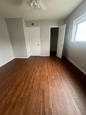 an empty room with wooden floor and ceiling fan