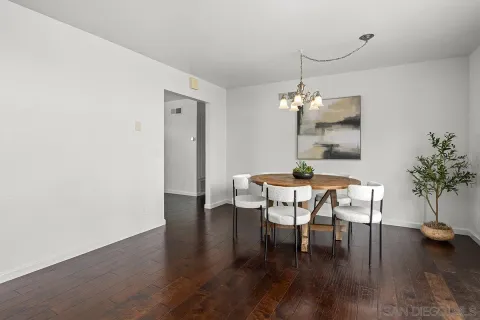 a dining room with wooden floor a chandelier a wooden table and chairs
