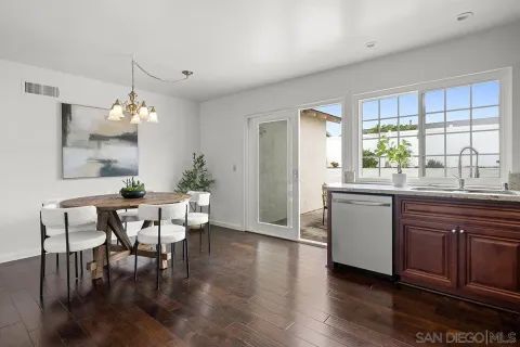 a dining room with wooden floor a chandelier a wooden table and chairs