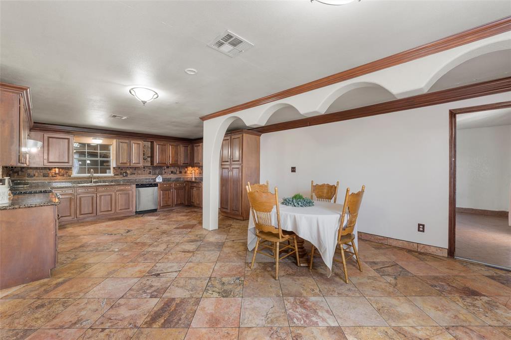 3433 West Tours Road West, TX 76691 - Photo 10 of 40 Dining space featuring light stone finish floors, ornamental molding, and arched walkways