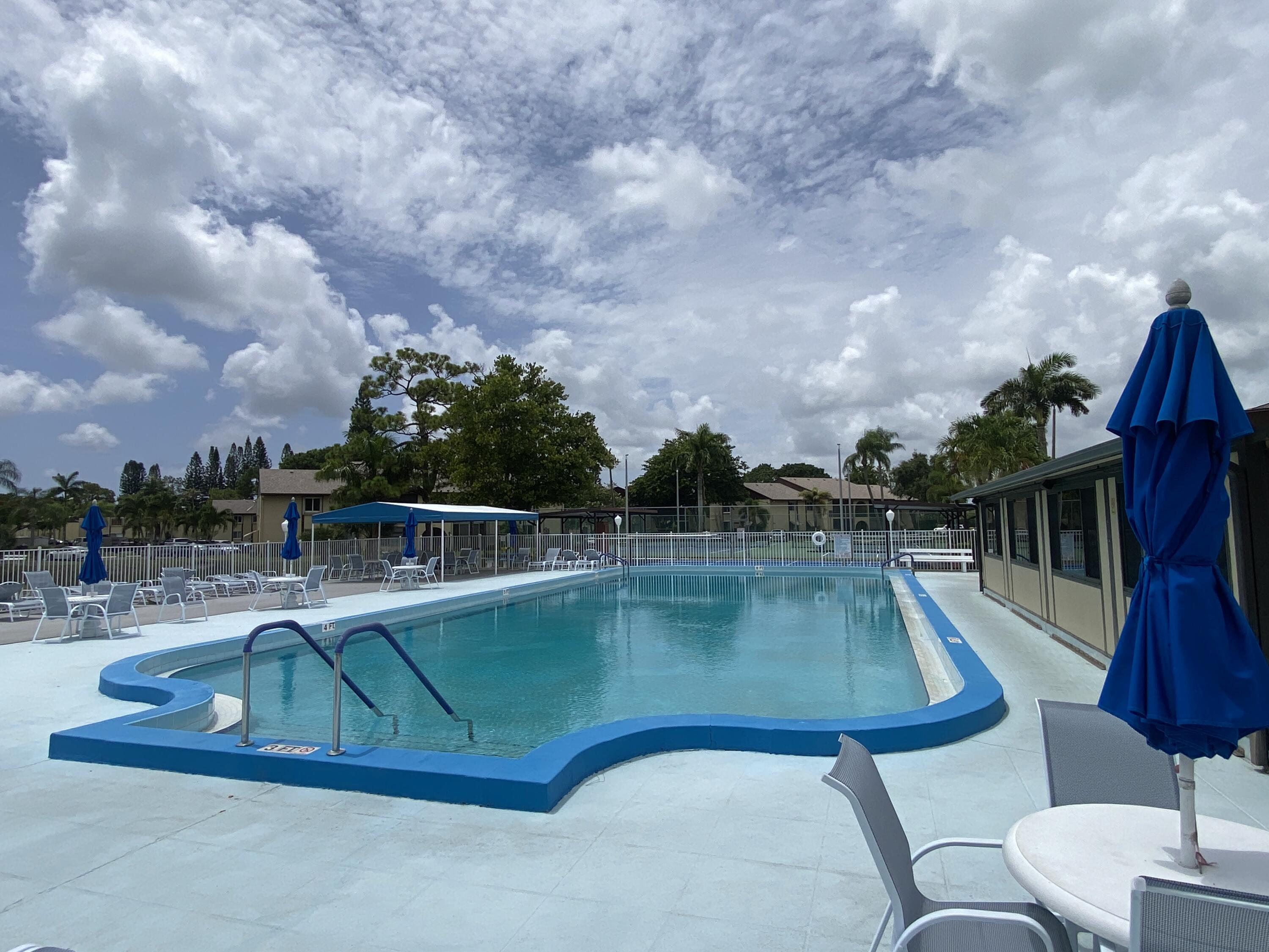 338 Pine Ridge Circle, Unit B2 Greenacres, FL 33463 - Photo 46 of 56 a view of a swimming pool with a yard from a corridor