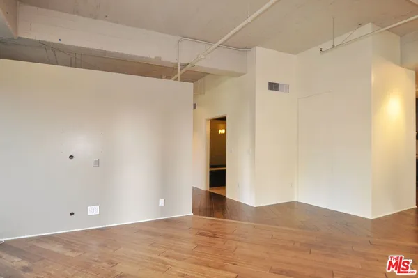 a view of an empty room with wooden floor and entryway