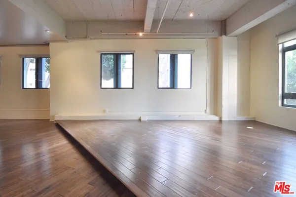 a view of an empty room with wooden floor and windows