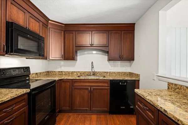 a kitchen with granite countertop a sink stove and cabinets