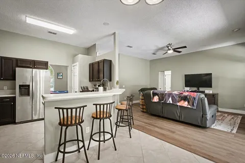 a living room with furniture a flat screen tv and a refrigerator