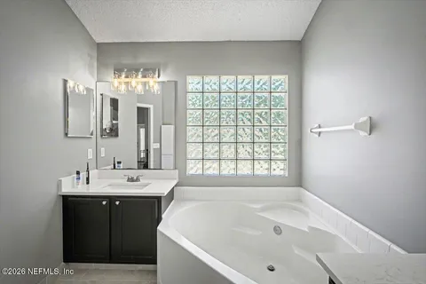 a bathroom with a tub sink and mirror