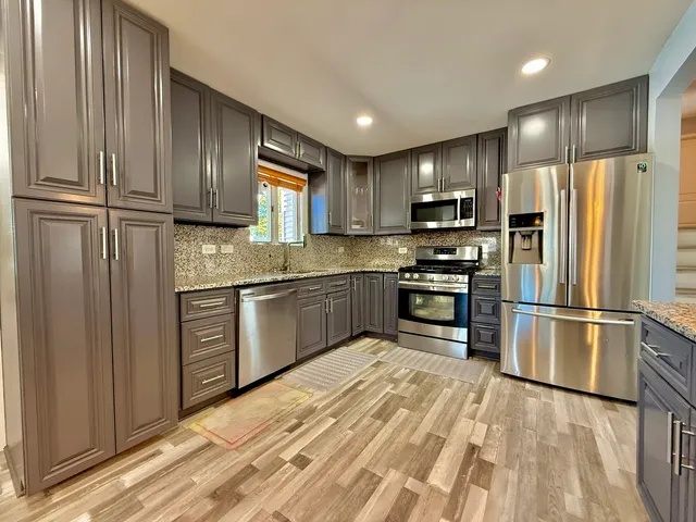 a kitchen with granite countertop stainless steel appliances and refrigerator