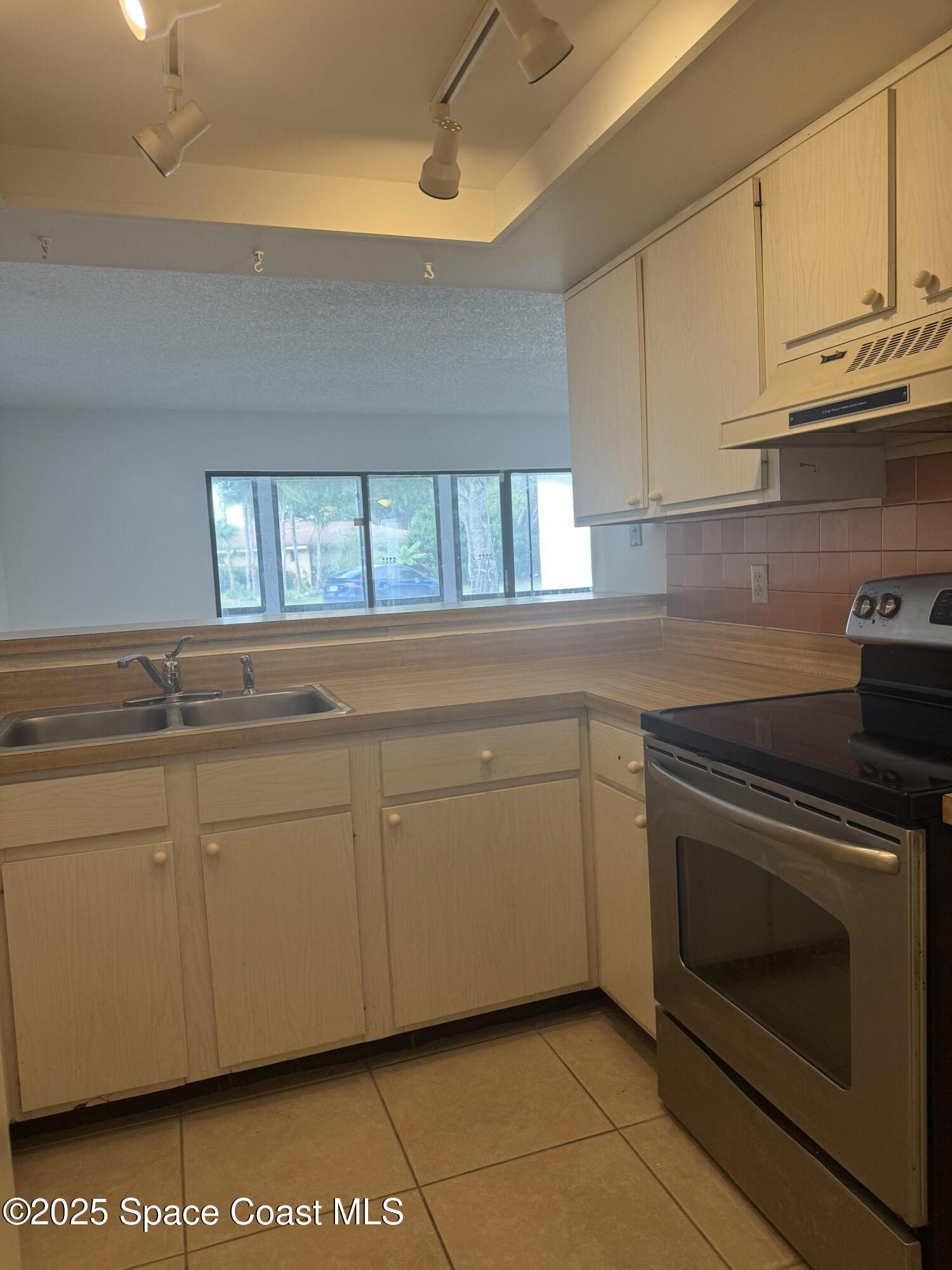 212 Augusta Way Melbourne, FL 32940 - Photo 24 of 49 a kitchen with granite countertop white cabinets stainless steel appliances a sink and a window
