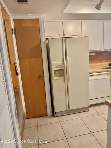 a view of a refrigerator in kitchen and an empty room in wooden floor