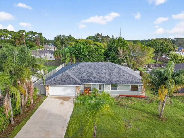 a aerial view of a house next to a big yard and large trees