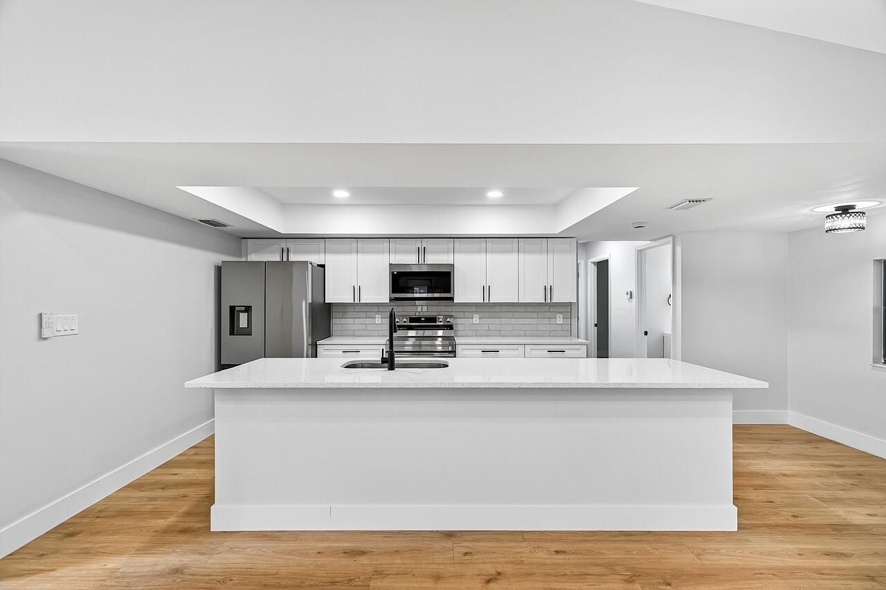 117 High Court Sebastian, FL 32958 - Photo 20 of 54 a large white kitchen with kitchen island a stove a refrigerator a sink and a dining table with wooden floor
