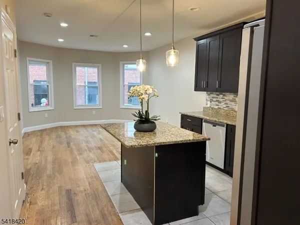 a room with kitchen island stainless steel appliances kitchen island granite countertop cabinets and wooden floor