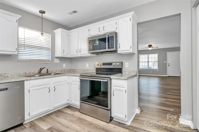 a kitchen with stainless steel appliances granite countertop a stove a sink and a microwave