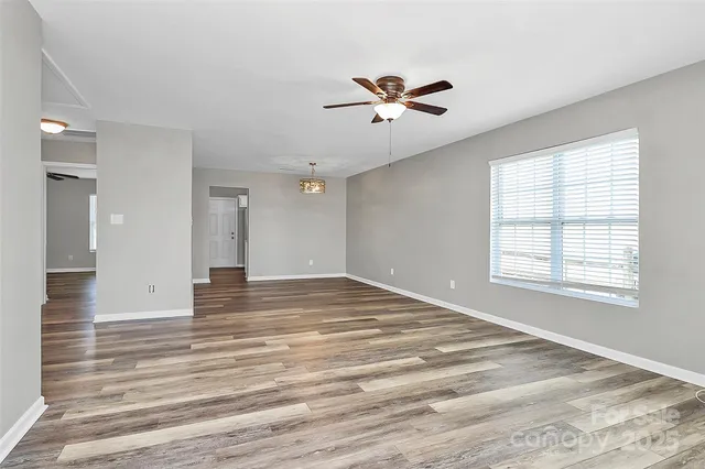 a view of an empty room with window and wooden floor