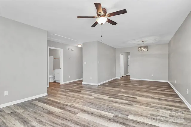 a view of an empty room with a ceiling fan and a kitchen