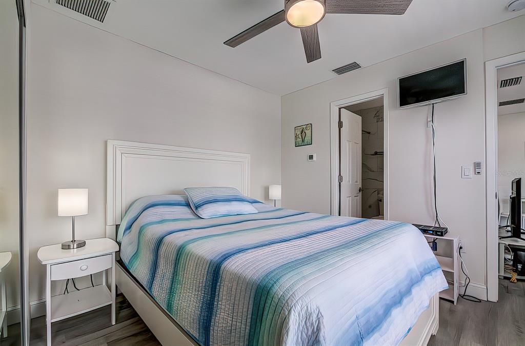 161 Medallion Boulevard, Unit E Madeira Beach, FL 33708 - Photo 13 of 19 a bedroom with a bed and a flat screen tv