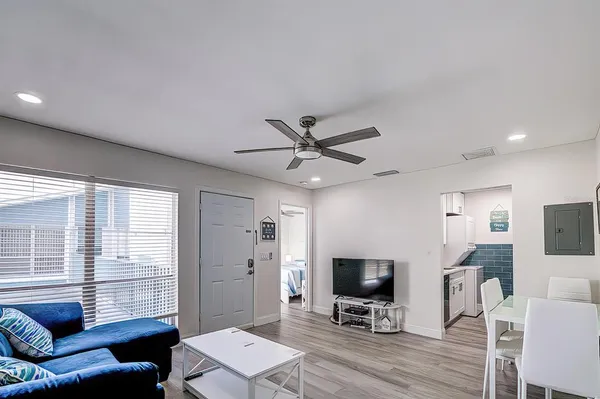 a living room with furniture a ceiling fan a flat screen tv and a large window