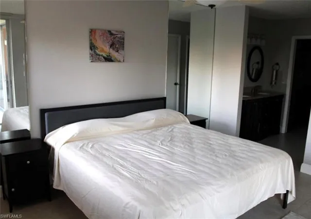 a large white bed in a bedroom next to a window