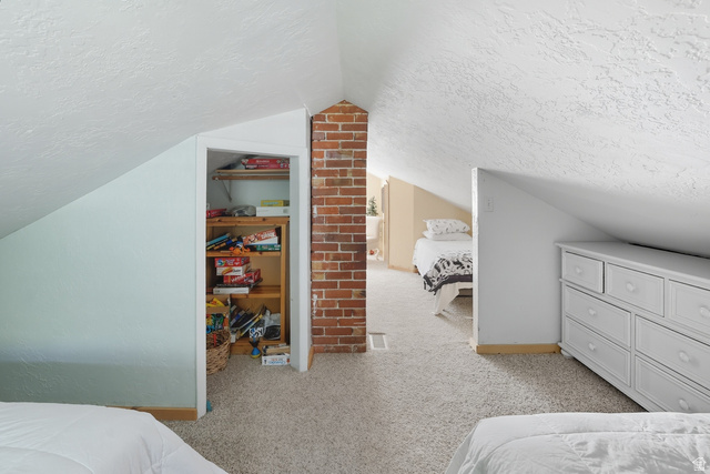667 North Rapid Creek Road Inkom, ID 83245 - Photo 21 of 29 Carpeted loft area featuring a prominent exposed brick chimney, angled ceilings, and a built-in closet with wooden shelving