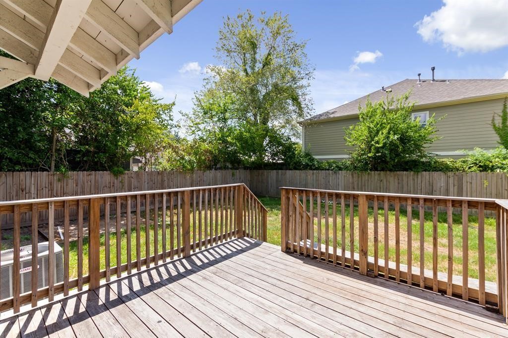 1305 Idylwild Street Houston, TX 77009 - Photo 21 of 31 This photo showcases a spacious wooden deck overlooking a fenced backyard with greenery and trees, offering a private and serene outdoor space ideal for relaxation or entertaining.