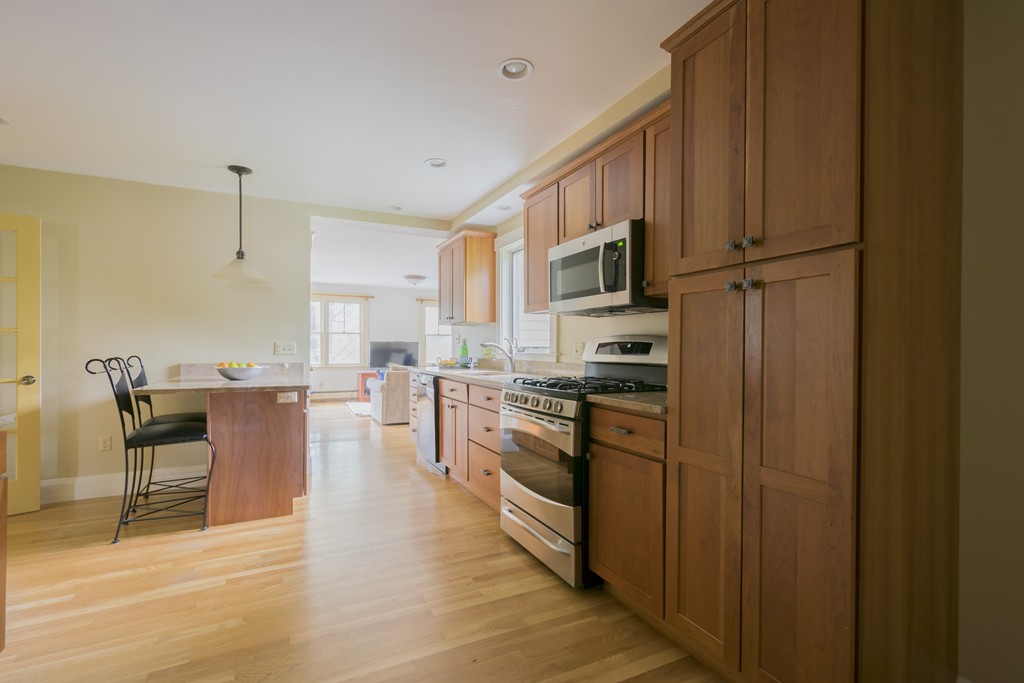 4 Reed Street Lexington, MA 02421 - Photo 11 of 30 a kitchen with stainless steel appliances granite countertop a refrigerator a stove top oven a sink dishwasher and white cabinets with wooden floor
