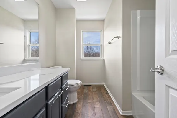 a bathroom with a sink a toilet a shower and a window