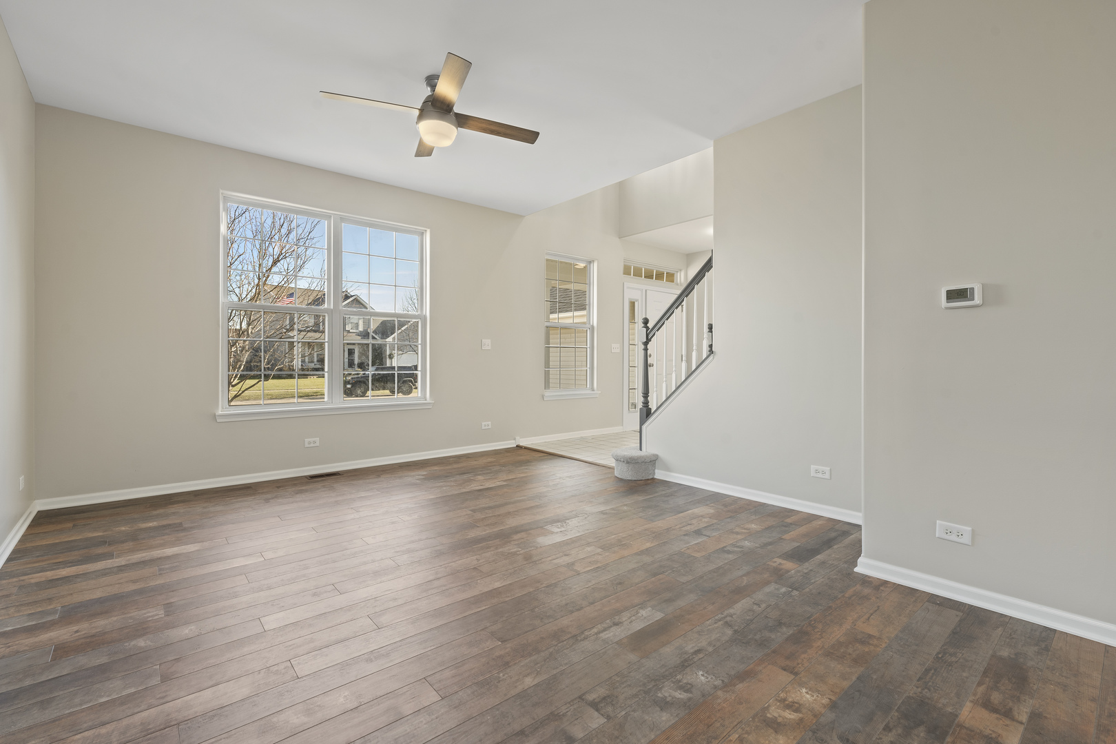 32804 Bending Creek Road Lakemoor, IL 60051 - Photo 4 of 42 a view of an empty room with wooden floor and a ceiling fan