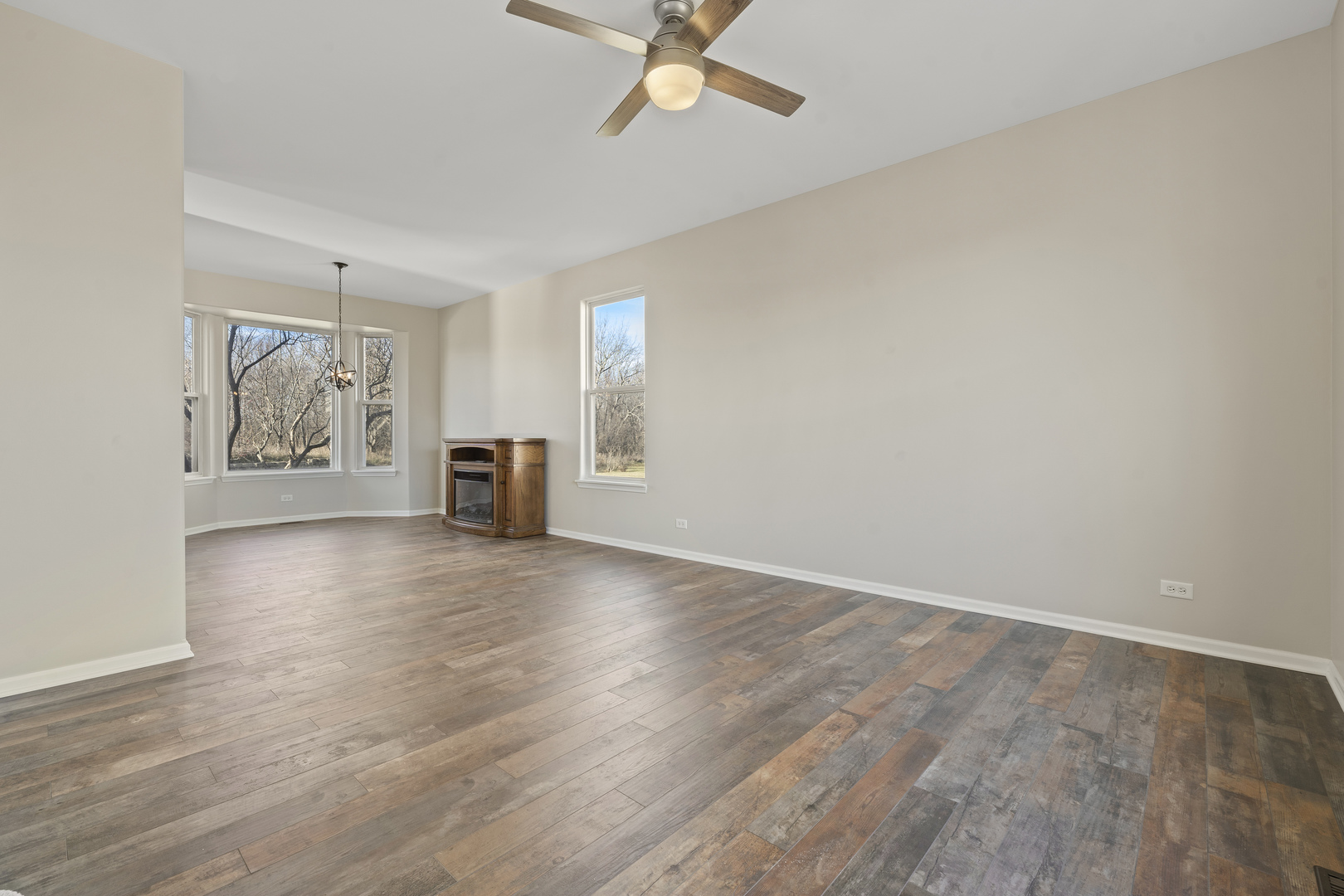 32804 Bending Creek Road Lakemoor, IL 60051 - Photo 5 of 42 an empty room with wooden floor chandelier fan and windows