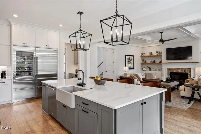 a kitchen with stainless steel appliances a sink a stove cabinets and living room view