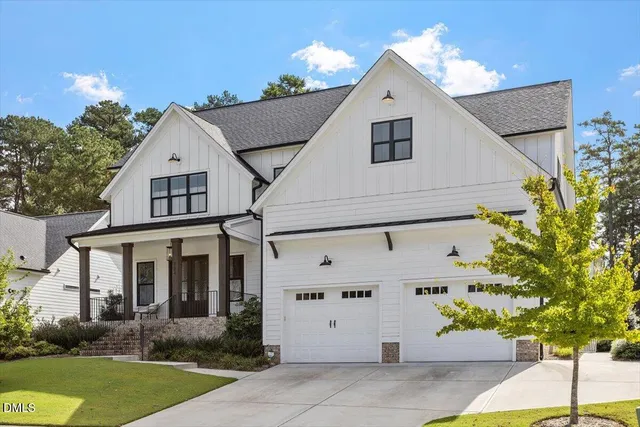 a view of a white house with potted plants and a yard