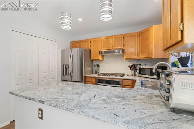 a kitchen with stainless steel appliances granite countertop a sink a stove and a refrigerator