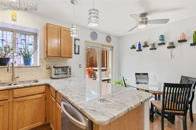 a kitchen with granite countertop cabinets a sink a stove and a dining table with wooden floor