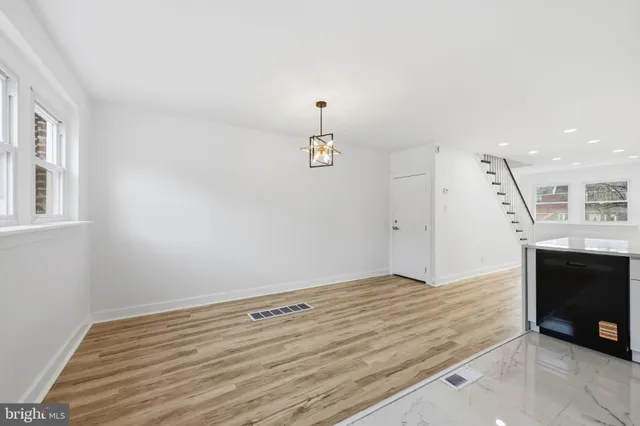 an empty room with wooden floor fireplace and windows